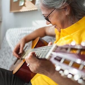 Close up of Senior woman playing guitar ay home