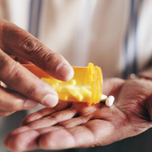 Hands, pills and bottle in closeup for person with drugs, routine and schedule for health in home. Elderly patient, container and pharma product for supplements, wellness or benefits in retirement
